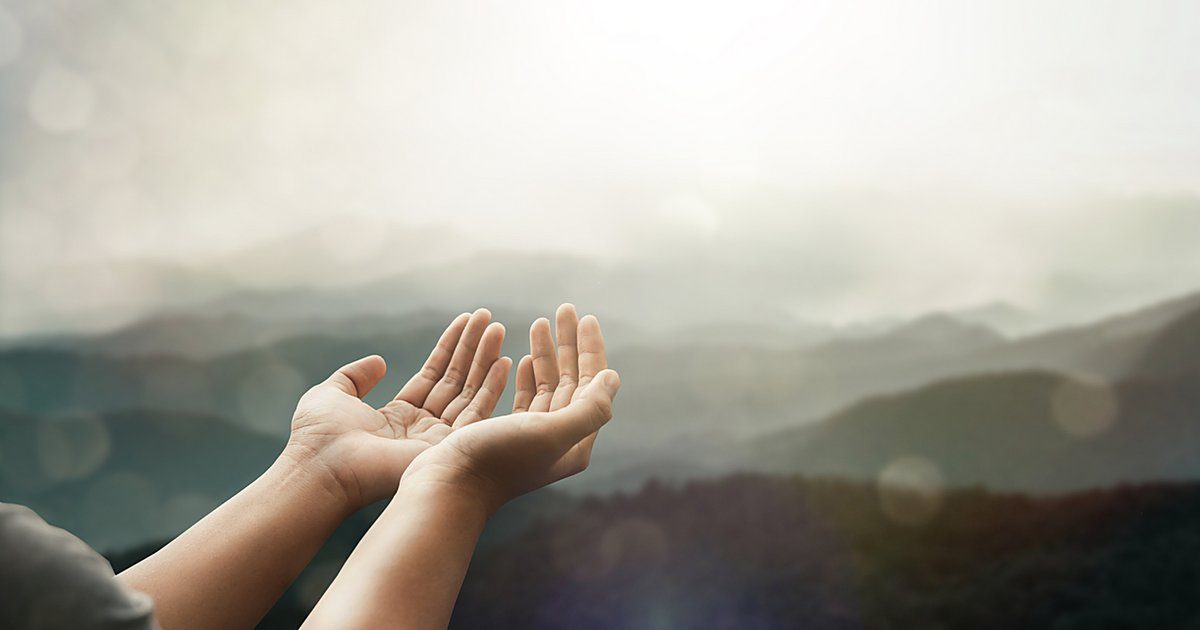 Open hands reaching towards misty mountains at sunrise, from Soul Essence Psychotherapy in Boulder, Colorado
