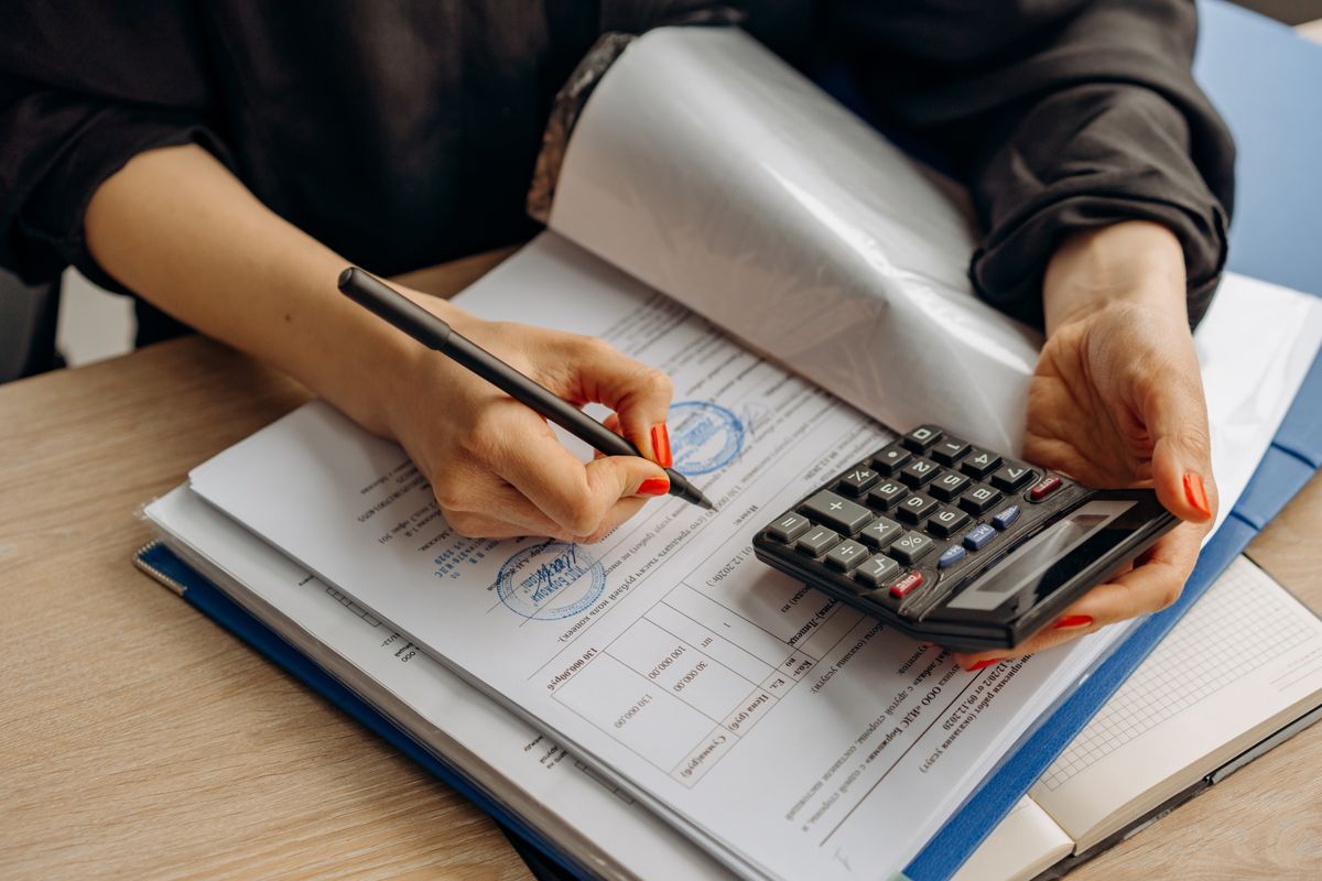 An accountant using a calculator and reviewing financial paperwork, representing compliance standards for finance content