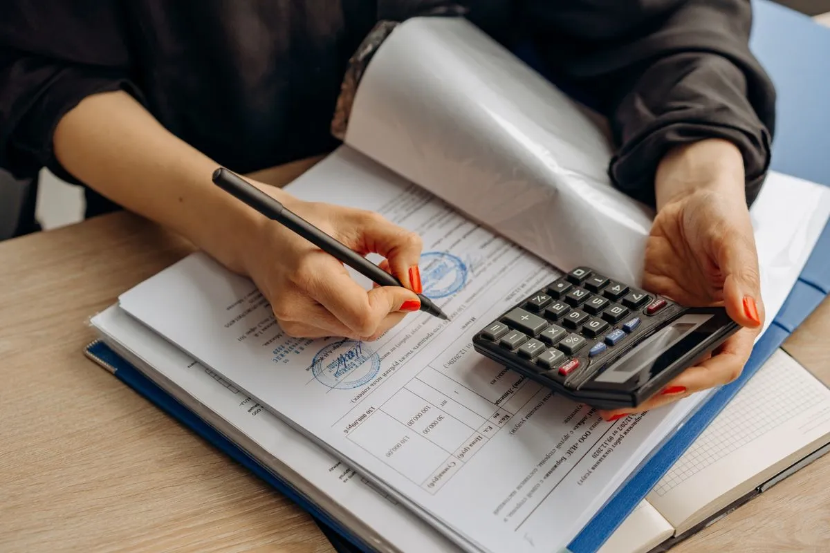 An accountant using a calculator and reviewing financial paperwork, representing compliance standards for finance content